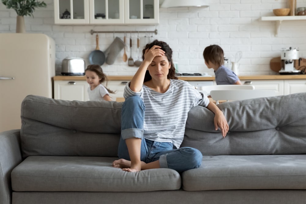 Stressed-woman-going-through-a-separation-with-kids-in-the-background